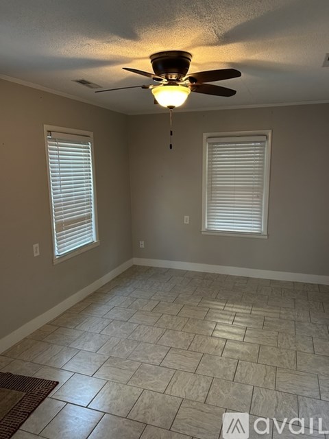A room with a ceiling fan and two windows.