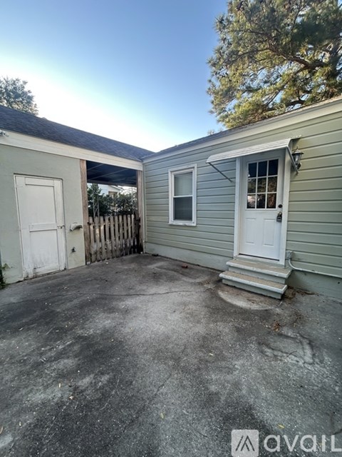 A small house with a white door and a grey wall.
