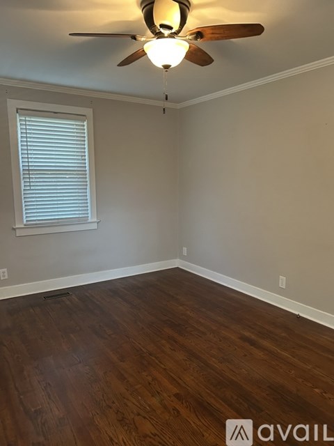 A room with a ceiling fan and wooden flooring.