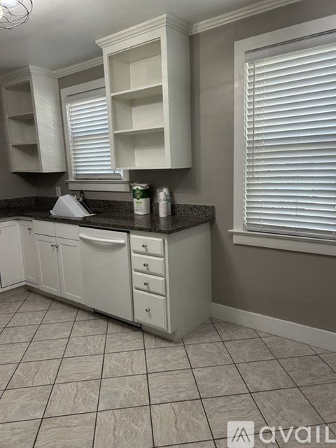 A kitchen with white cabinets and a black countertop.