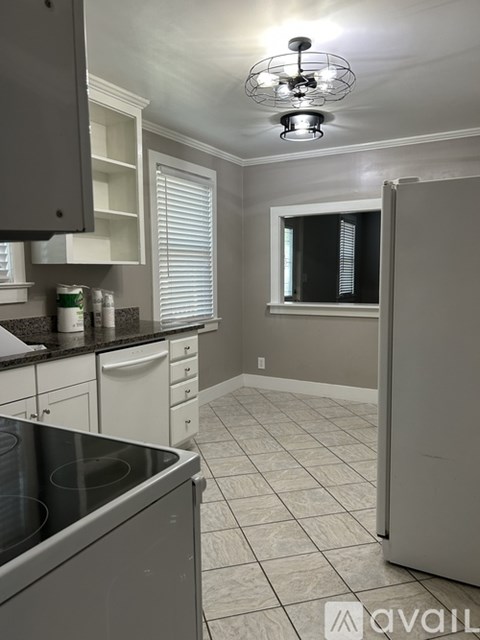A kitchen with a stainless steel dishwasher and white cabinets.