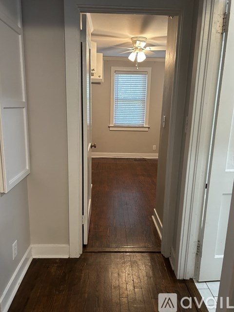 A hallway with a wooden floor and a ceiling fan.