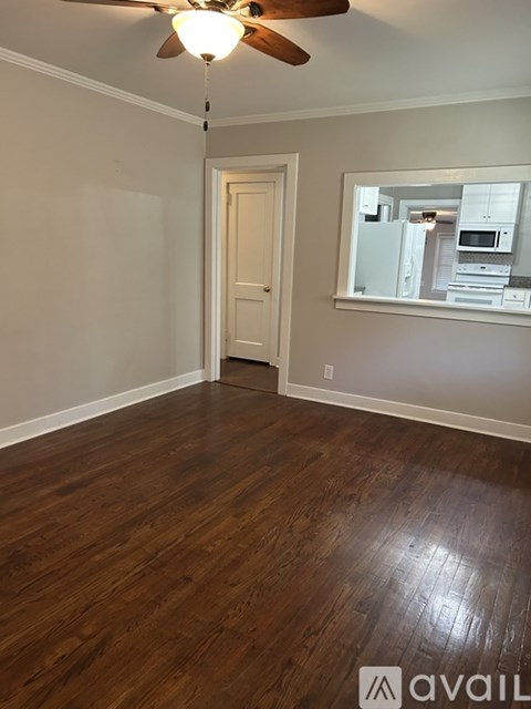 A room with a ceiling fan and wooden flooring.