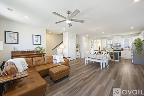 A living room with a brown leather couch and a white dining table.