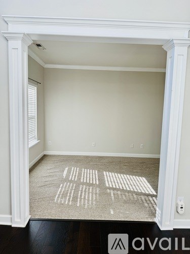 A room with a carpet and a doorway leading to another room.
