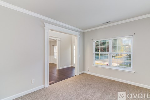 A room with a carpeted floor and a window with blinds.