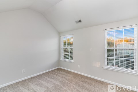 A room with a carpeted floor and a window with blinds.
