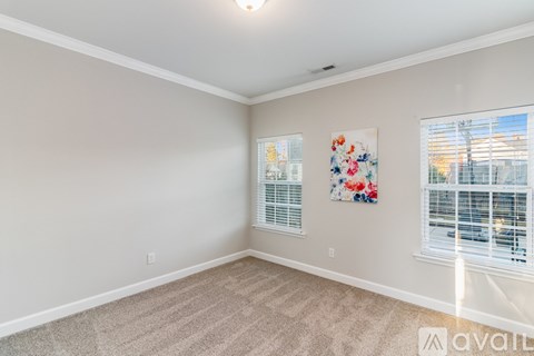 A room with a carpeted floor and a painting on the wall.