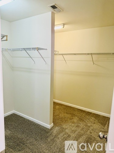 A room with a carpeted floor and a wall-mounted clothes rack.