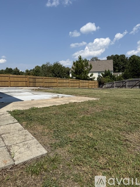 A backyard with a wooden fence and a concrete path.
