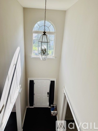 A hallway with a white door and a hanging light fixture.