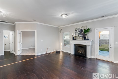 A large, empty room with a fireplace and wood flooring.