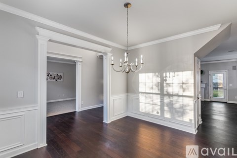 A large empty room with wood floors and a chandelier.