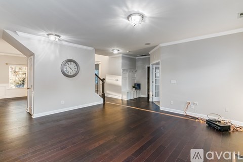 A large, empty room with a clock on the wall and wooden flooring.