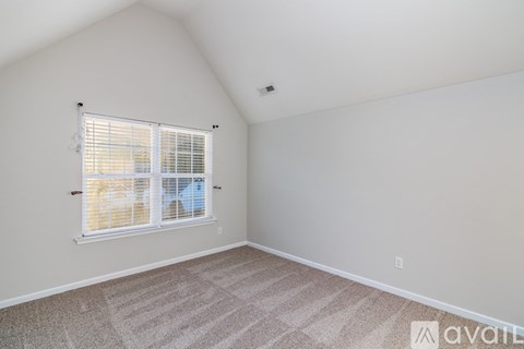 A room with a carpeted floor and a window with blinds.