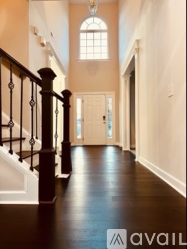A hallway with a staircase and a chandelier.