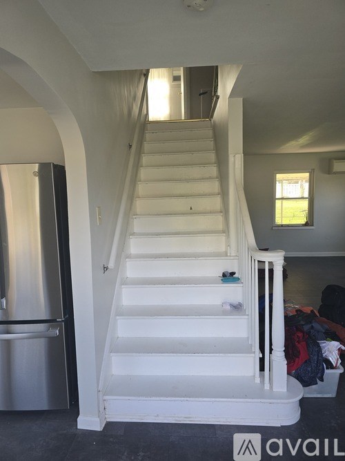 A white staircase with a black handrail and a window on the landing.
