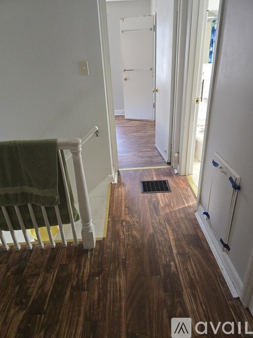 A hallway with wood flooring and white walls.