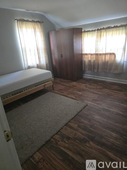 A bedroom with a bed, wardrobe, and a rug.