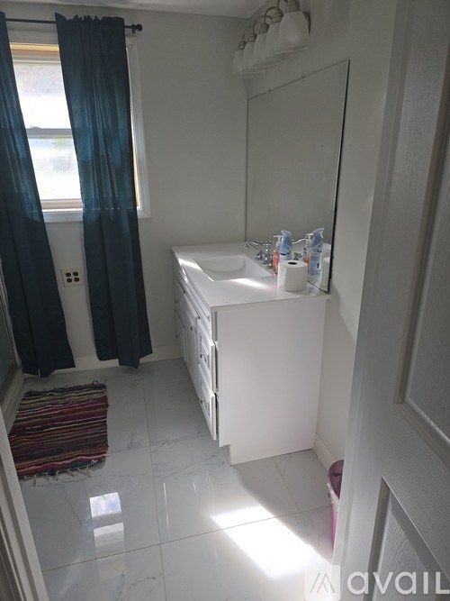 A bathroom with a white sink and a window with blue curtains.
