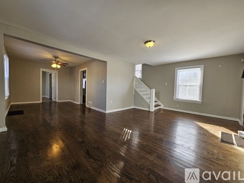A spacious living room with wood flooring and a staircase leading to the second floor.