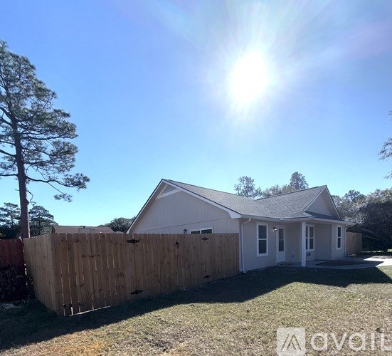 A house with a wooden fence and a tree in front of it.