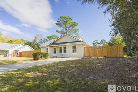 A house with a wooden fence and a tree in front of it.