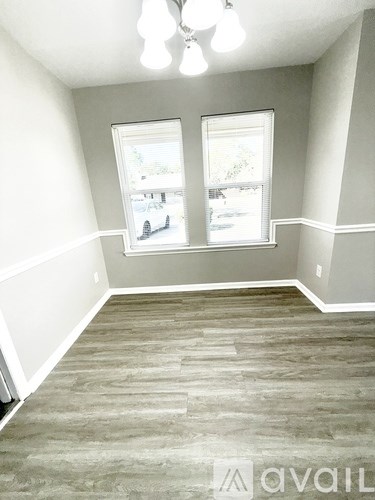 A room with a window and a wooden floor.