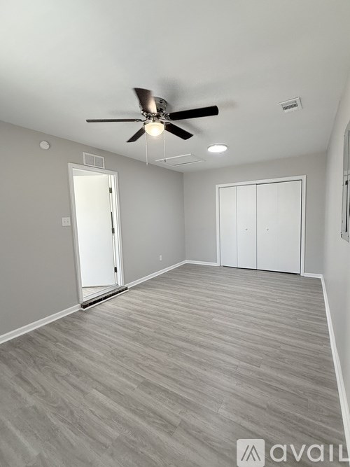A spacious room with a ceiling fan and light fixture, carpeted flooring, and two white doors.