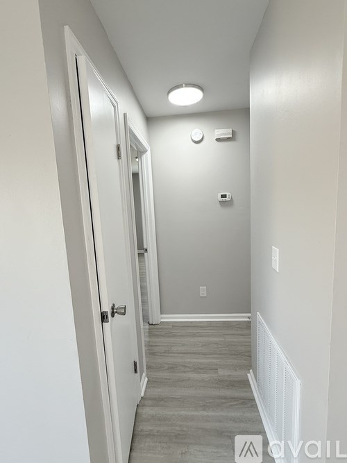 A long hallway with a white door and a white wall.