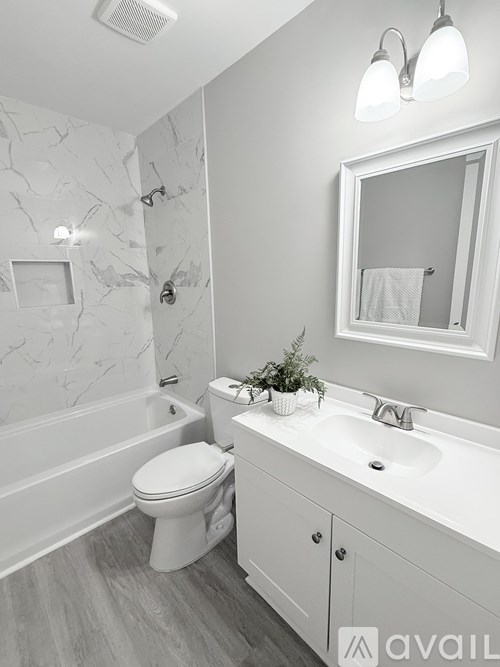 A white bathroom with a marble wall and a toilet.