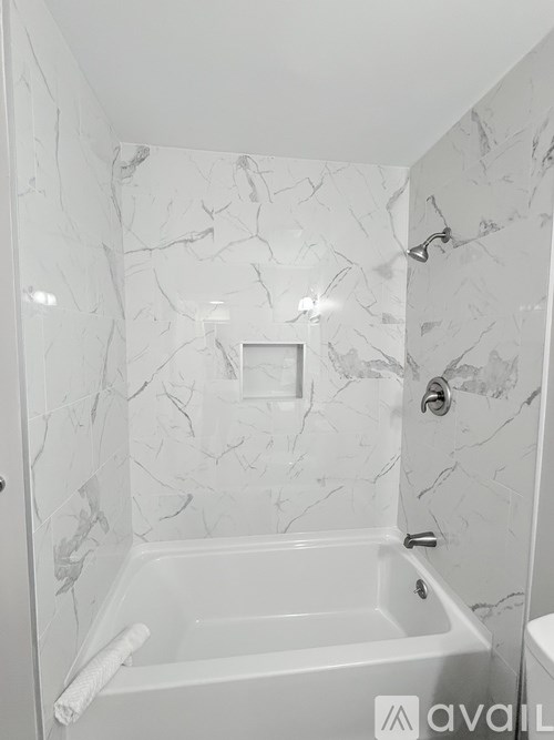 A white marble bathroom with a tub and a toilet.