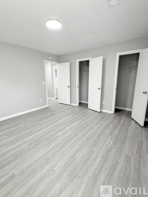 A room with three doors and a wooden floor.