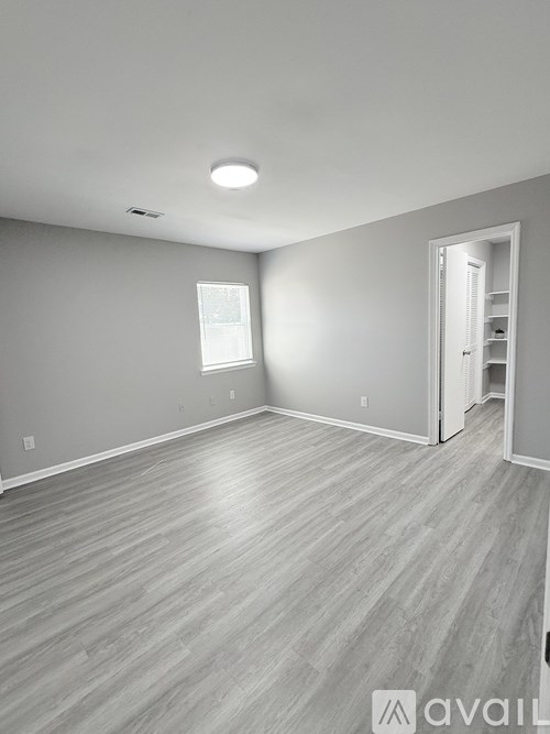 A spacious room with wooden flooring and a doorway leading to another room.