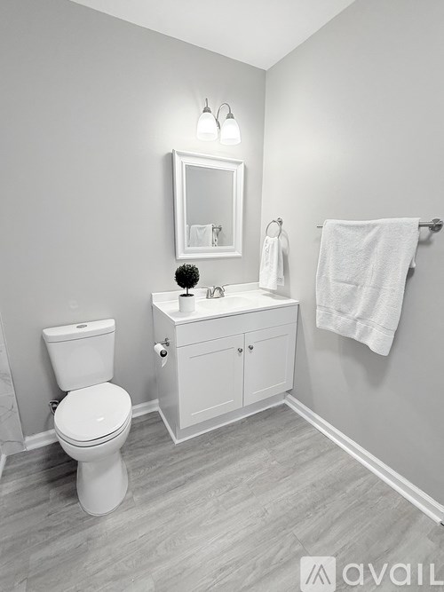 A white toilet sits next to a white cabinet with a mirror above it.