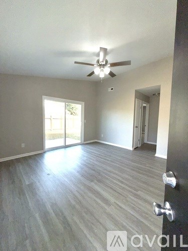 A room with a ceiling fan and sliding glass doors.