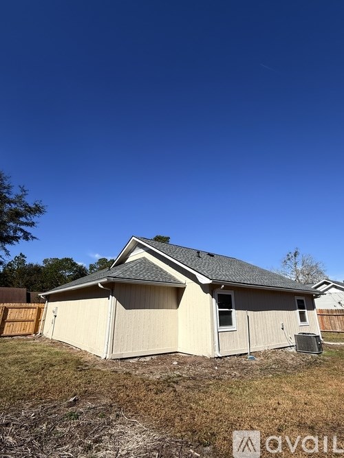 A small house with a brown fence and a tree in the background.