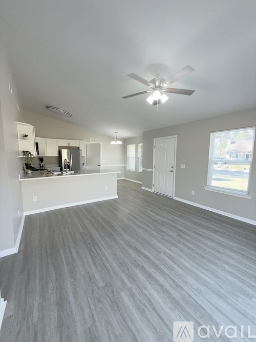 A spacious room with a ceiling fan and grey flooring.
