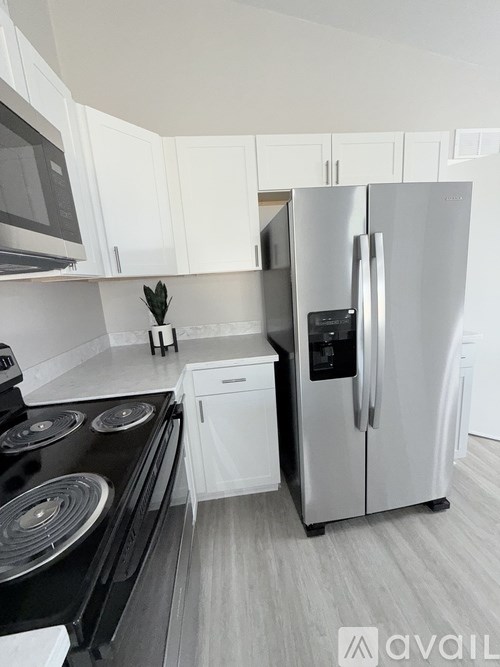 A kitchen with a black stove top oven and a silver refrigerator.