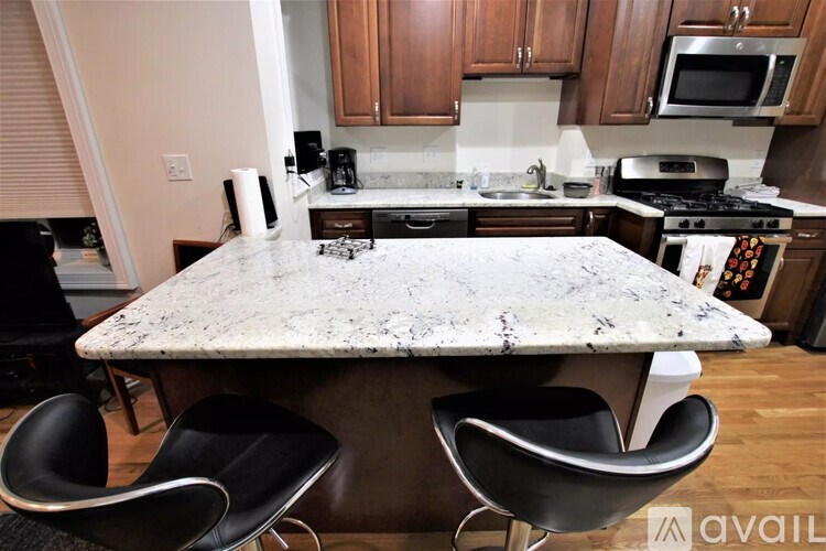 A kitchen with a granite countertop and black chairs.