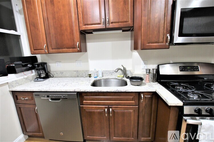A kitchen with wooden cabinets and a stainless steel dishwasher.