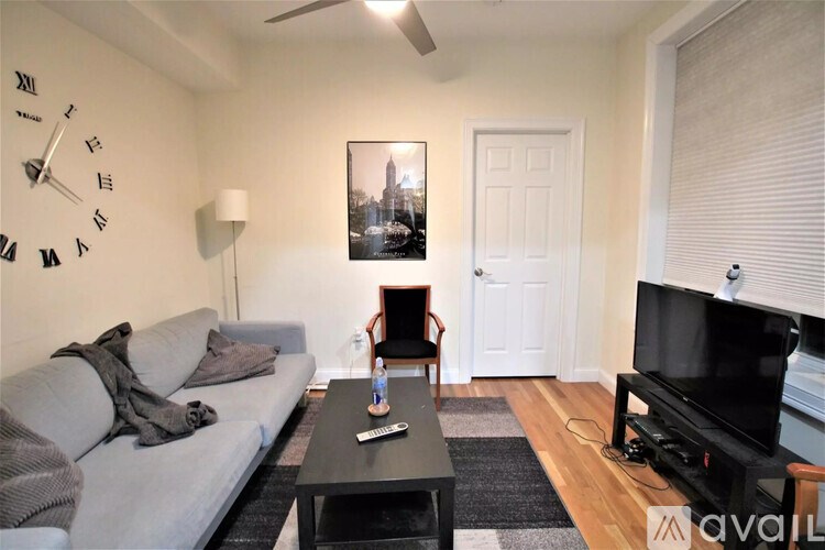 A living room with a grey couch, a black coffee table, a television, and a picture on the wall.