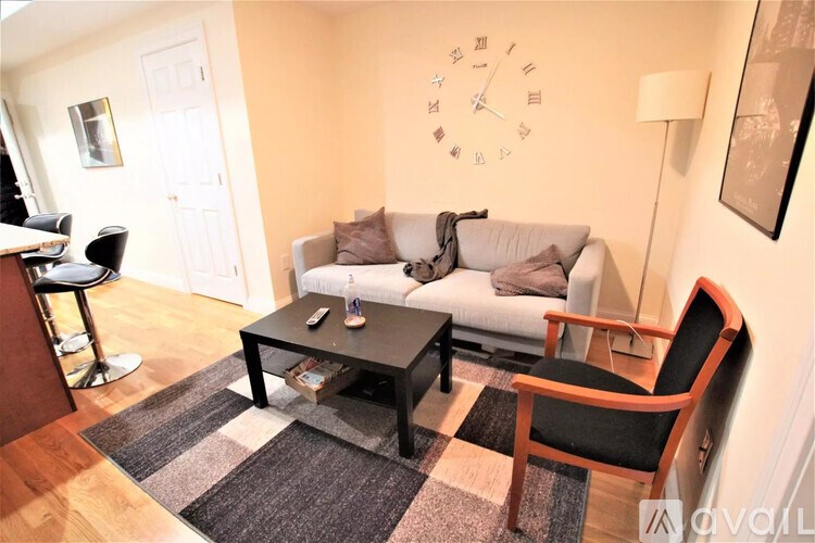 A living room with a couch, a coffee table, and a clock on the wall.