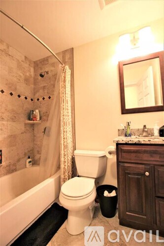 A bathroom with a toilet, a tub, and a mirror.