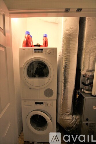 A washing machine with a bottle of detergent on top of it.