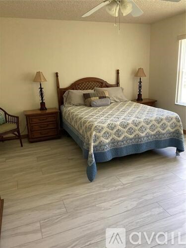 A bedroom with a bed, two lamps, and a ceiling fan.