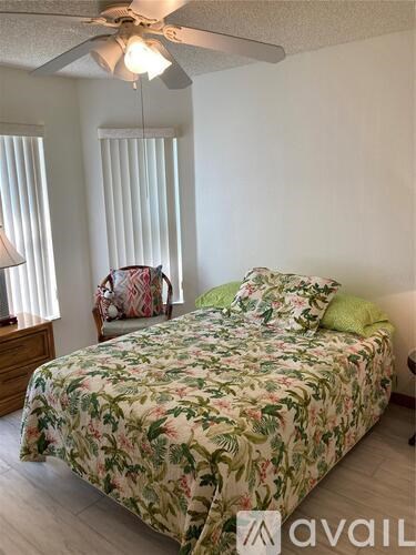 A bedroom with a floral bedspread and a ceiling fan.