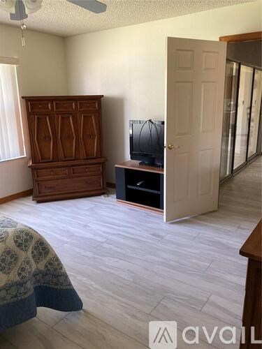 A room with a wooden dresser and a television on a stand.
