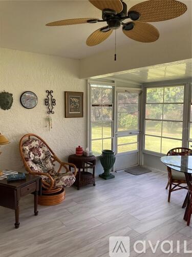 A living room with a fan, chair, and table.