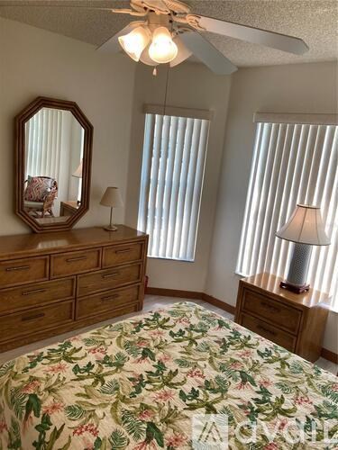 A bedroom with a floral bedspread and a wooden dresser.